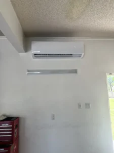 Indoor wall-mounted mini split unit installed above a garage workspace